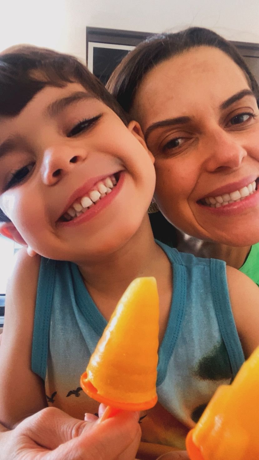 Momento leve entre Débora e criança saboreando picolé de fruta